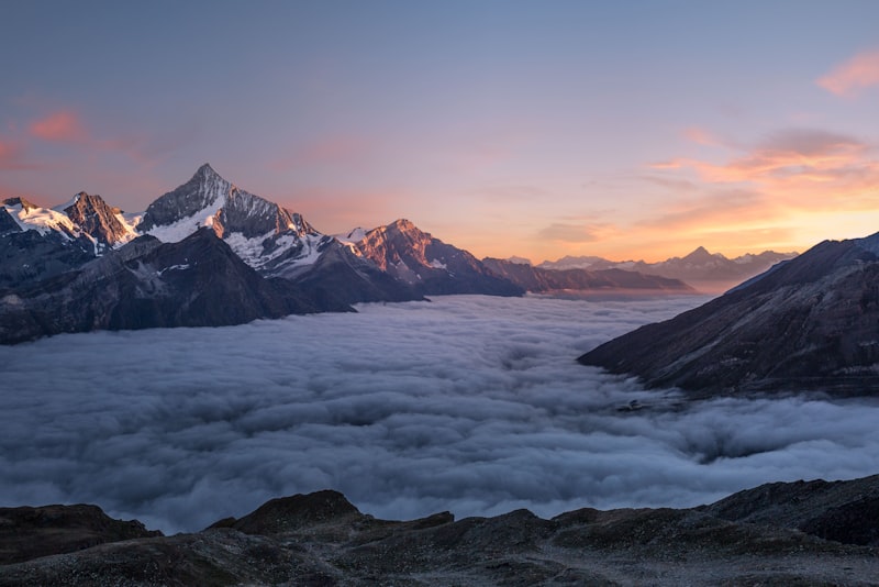 A hiker silhouetted against a glowing mountain sunrise holding a camera